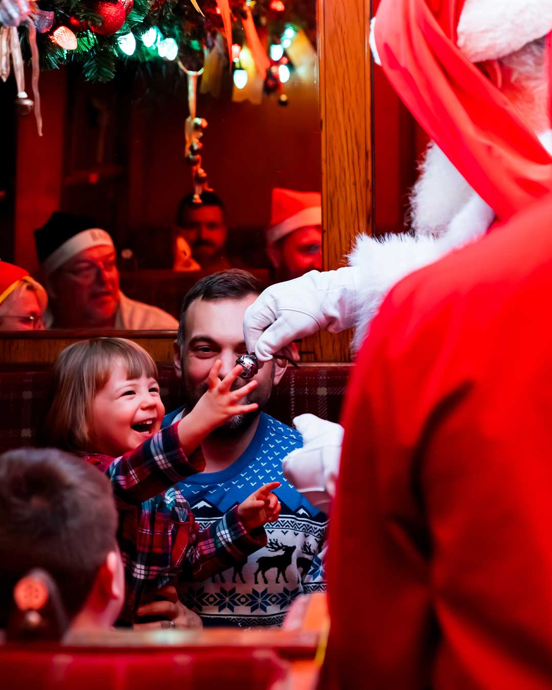 santa handing out bells on board the polar express train ride